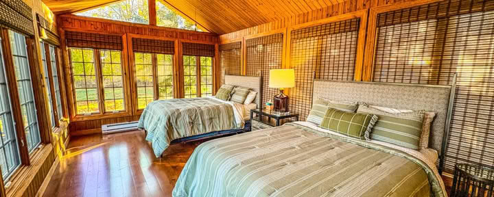 Een queensize bed in een gedeelde slaapkamer met twee queensize bedden en gedeelde badkamer in een modern meerhuis